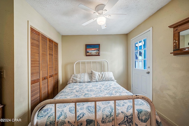 bedroom featuring ceiling fan, a textured ceiling, a closet, and a textured wall