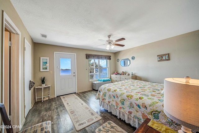 bedroom featuring baseboards, visible vents, a ceiling fan, dark wood-type flooring, and a textured ceiling