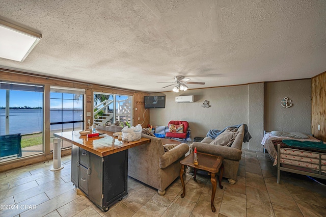 living room featuring a textured wall, ceiling fan, a water view, a textured ceiling, and an AC wall unit