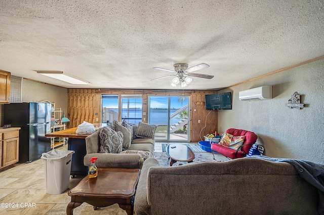 living room featuring a wall unit AC, a textured wall, a textured ceiling, and ceiling fan