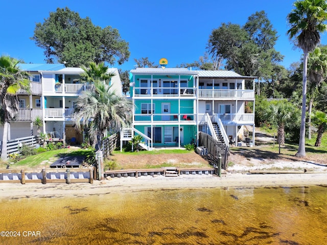 back of house featuring stairway, a water view, and a balcony