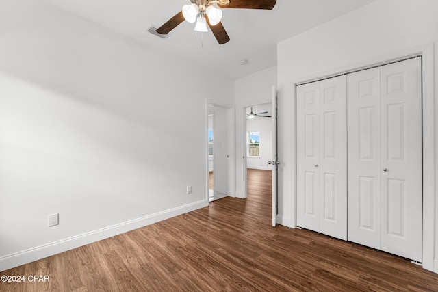 unfurnished bedroom with dark wood-type flooring, ceiling fan, and a closet