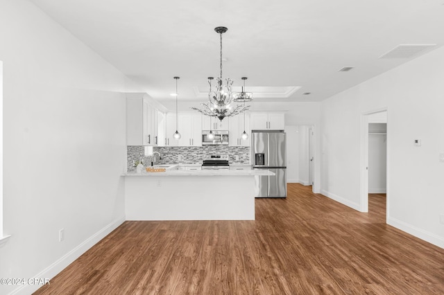 kitchen with kitchen peninsula, appliances with stainless steel finishes, white cabinetry, dark hardwood / wood-style floors, and pendant lighting