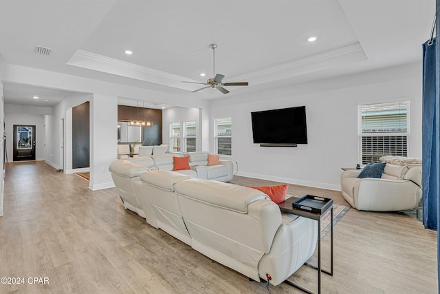 living room with light wood-type flooring, a healthy amount of sunlight, and a tray ceiling