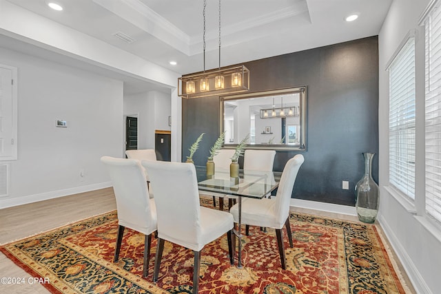 dining space featuring hardwood / wood-style flooring, crown molding, and a raised ceiling