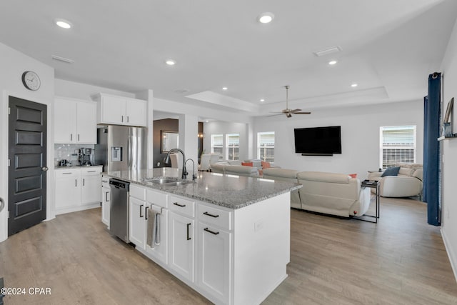 kitchen with an island with sink, white cabinets, sink, and a healthy amount of sunlight