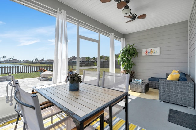 sunroom featuring ceiling fan and a water view