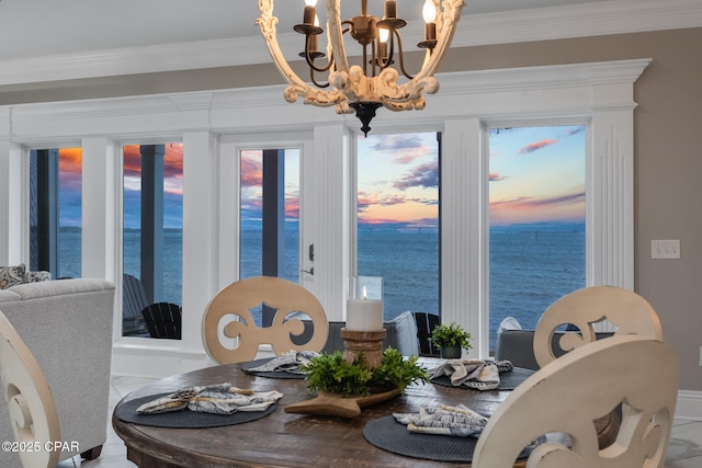 dining room with a water view, a chandelier, and ornamental molding