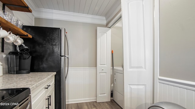 kitchen with washer / dryer, white cabinets, light hardwood / wood-style floors, crown molding, and stainless steel appliances