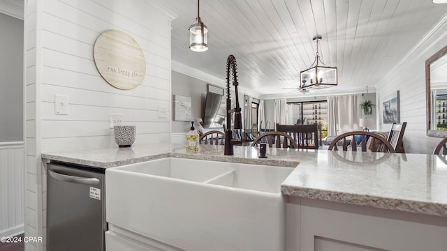 kitchen featuring stainless steel dishwasher, light stone counters, hanging light fixtures, and wood walls