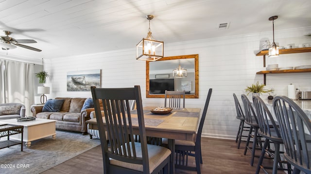 dining area with ornamental molding, dark wood-type flooring, and ceiling fan with notable chandelier