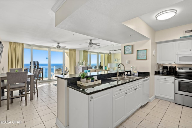 kitchen featuring white appliances, a water view, kitchen peninsula, and sink