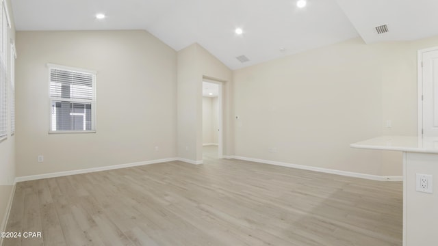 unfurnished room featuring light wood-type flooring and vaulted ceiling