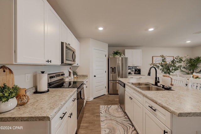 kitchen featuring white cabinetry, stainless steel appliances, sink, and light wood-type flooring