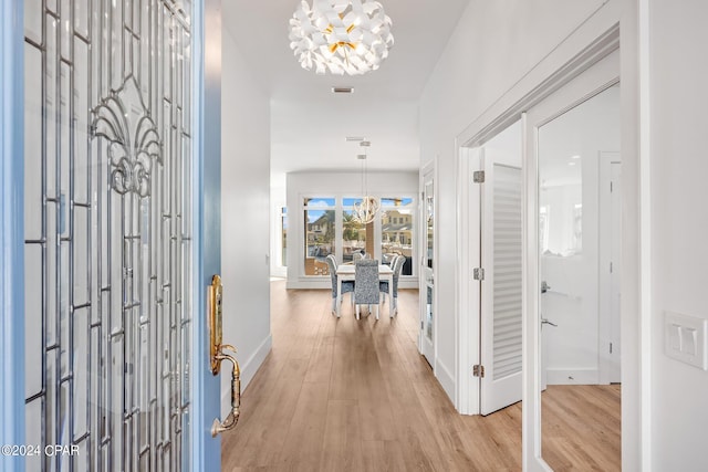 foyer with light hardwood / wood-style floors and a notable chandelier