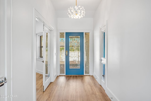 doorway to outside featuring an inviting chandelier and light hardwood / wood-style floors