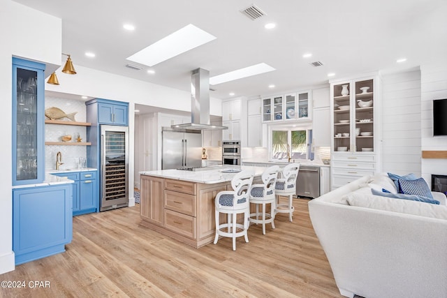 kitchen with tasteful backsplash, blue cabinets, stainless steel appliances, range hood, and a center island