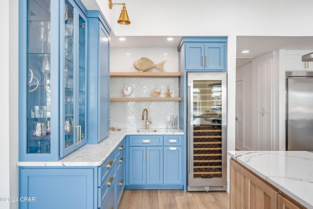 bar featuring light hardwood / wood-style floors, light stone counters, backsplash, and built in refrigerator