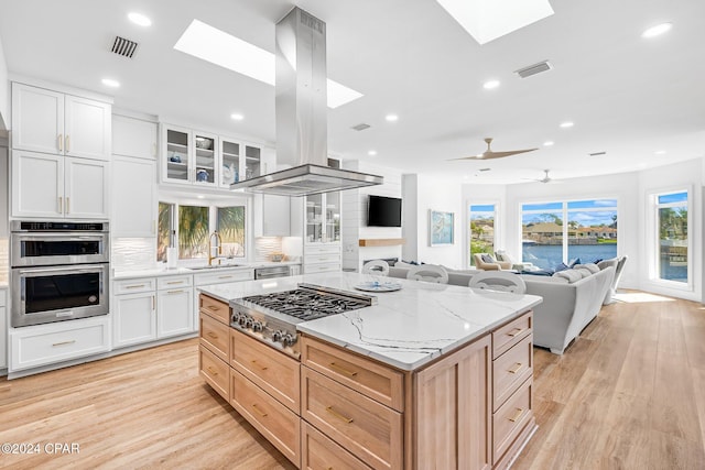 443 Wahoo Rd, Panama City Beach, FL 32408 - kitchen with a skylight, stainless steel appliances, island range hood, a sink, and light stone countertops