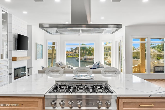 443 Wahoo Rd, Panama City Beach, FL 32408 - kitchen with island exhaust hood, open floor plan, stainless steel gas cooktop, recessed lighting, and a glass covered fireplace