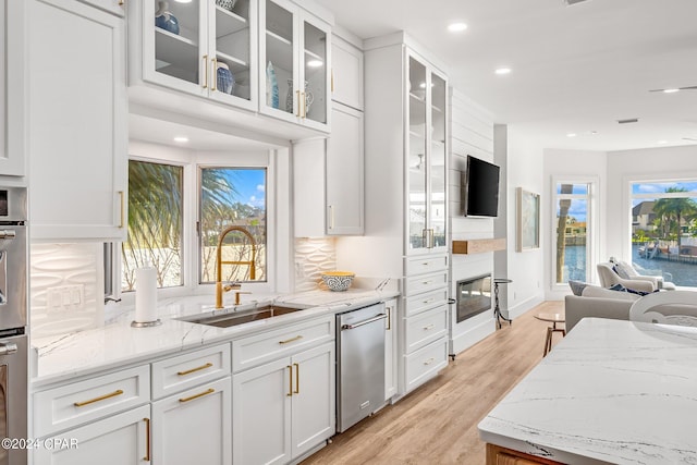 kitchen with decorative backsplash, stainless steel appliances, sink, white cabinets, and light hardwood / wood-style floors