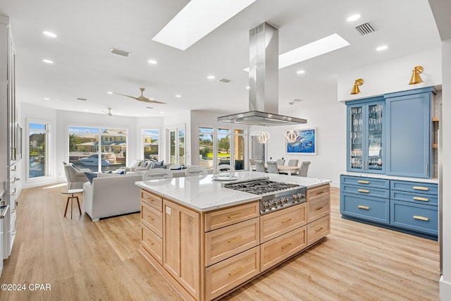 kitchen featuring stainless steel gas cooktop, blue cabinetry, light brown cabinets, and light hardwood / wood-style floors