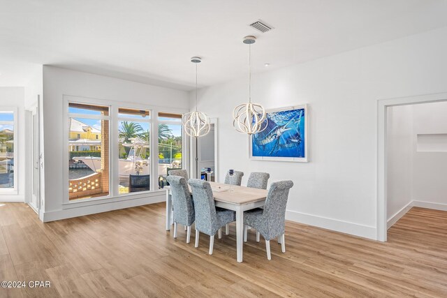 443 Wahoo Rd, Panama City Beach, FL 32408 - dining area with light wood-style floors, a chandelier, and baseboards
