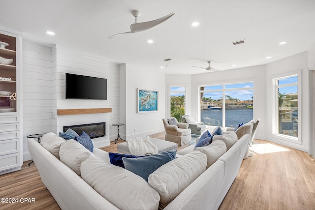 living room featuring light hardwood / wood-style flooring, a large fireplace, and ceiling fan