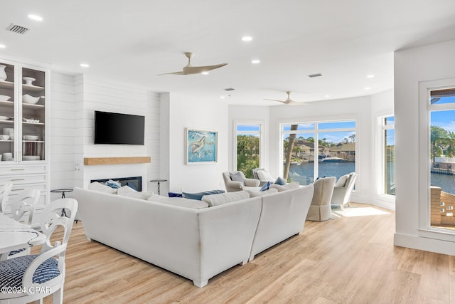 living room featuring light hardwood / wood-style flooring, a fireplace, and ceiling fan