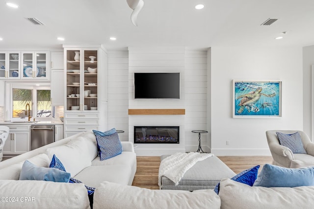 living room with sink, light hardwood / wood-style flooring, and a large fireplace