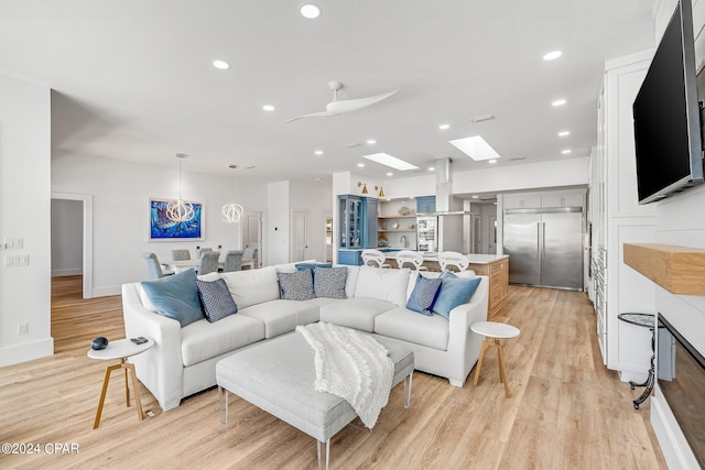 living room with light hardwood / wood-style flooring, ceiling fan, and a skylight