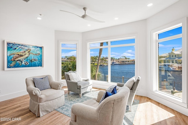 living room with a water view, light hardwood / wood-style floors, and a wealth of natural light