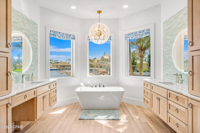 bathroom with a bathing tub, a healthy amount of sunlight, hardwood / wood-style flooring, and vanity