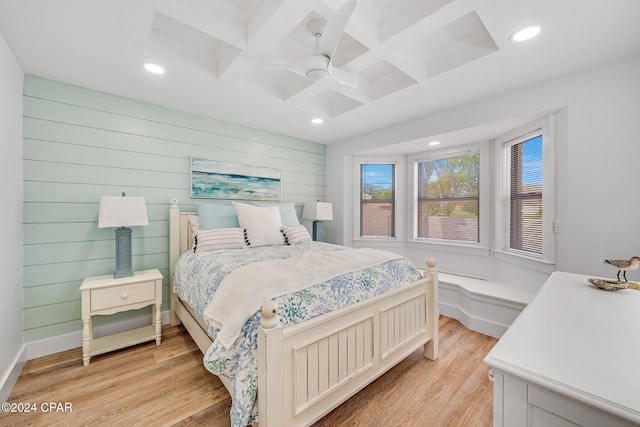 bedroom featuring coffered ceiling, beam ceiling, light hardwood / wood-style flooring, ceiling fan, and wood walls