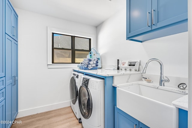 laundry room featuring sink, washer and clothes dryer, light hardwood / wood-style flooring, and cabinets