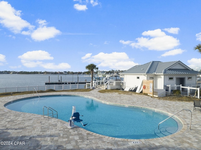 view of swimming pool featuring a water view, a patio, and a boat dock