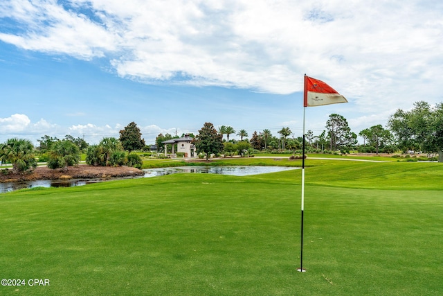 surrounding community with a water view and a lawn