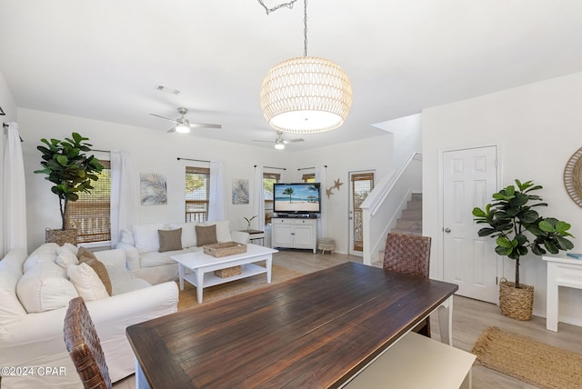 living room featuring ceiling fan with notable chandelier and light wood-type flooring