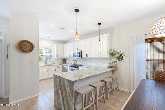 kitchen featuring white cabinetry, sink, light stone counters, kitchen peninsula, and appliances with stainless steel finishes