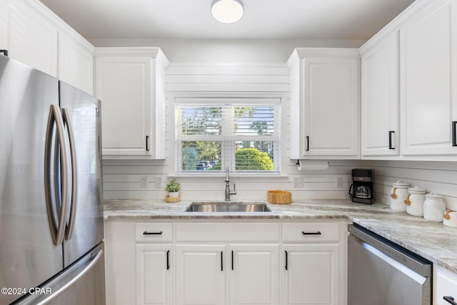 kitchen with light stone countertops, sink, white cabinets, and stainless steel appliances