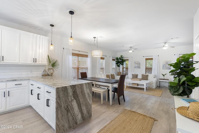 kitchen with white cabinets, decorative light fixtures, light wood-type flooring, and kitchen peninsula