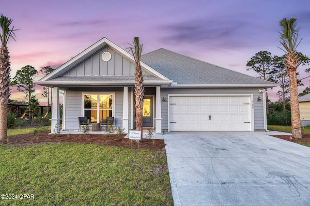 view of front facade featuring driveway, an attached garage, a yard, a porch, and board and batten siding