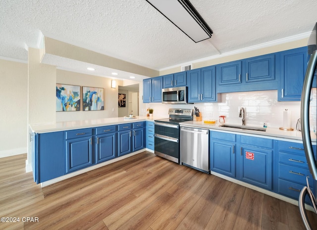 kitchen with blue cabinets, crown molding, sink, light hardwood / wood-style flooring, and appliances with stainless steel finishes