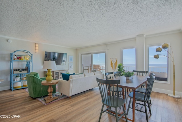 dining area featuring light wood-style floors, baseboards, and a textured ceiling