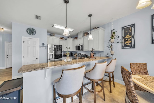 kitchen featuring kitchen peninsula, white cabinetry, pendant lighting, and appliances with stainless steel finishes