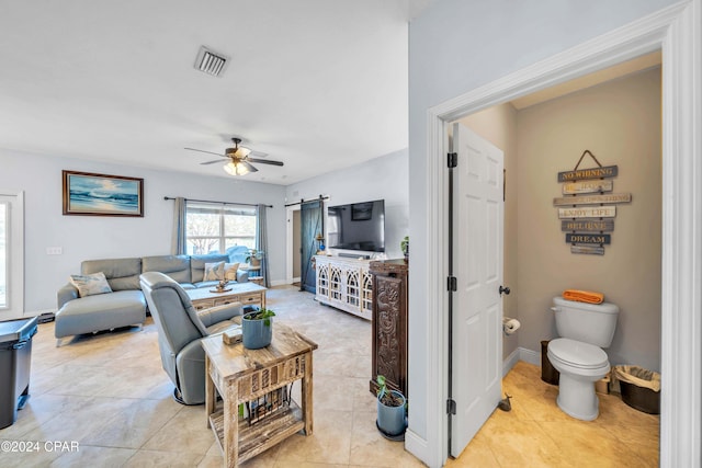 living room featuring a barn door, ceiling fan, and light tile patterned floors