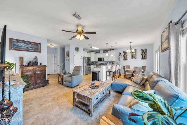 tiled living room with ceiling fan with notable chandelier