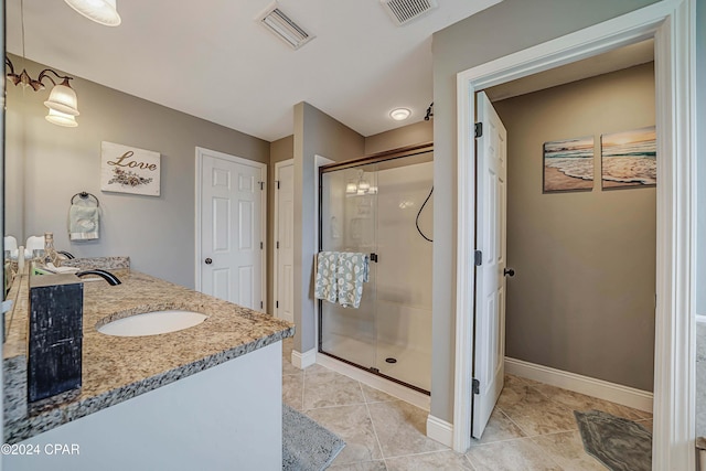 bathroom with a shower with shower door, vanity, and tile patterned floors