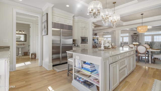 kitchen featuring light wood-style floors, crown molding, decorative columns, built in appliances, and light stone countertops