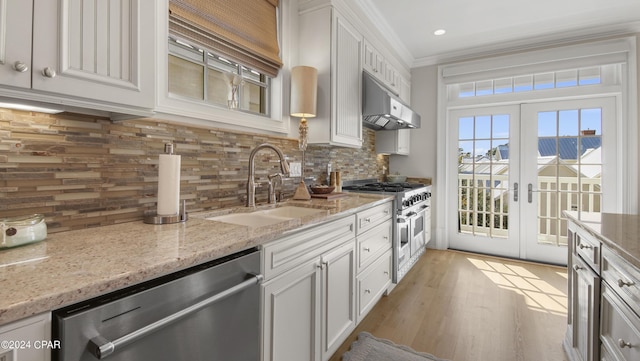 kitchen featuring a sink, ornamental molding, stainless steel appliances, under cabinet range hood, and tasteful backsplash